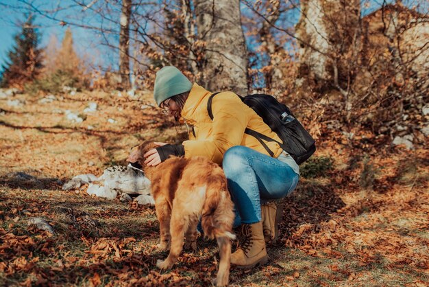 Mujer joven con perro en un día soleado de senderismo