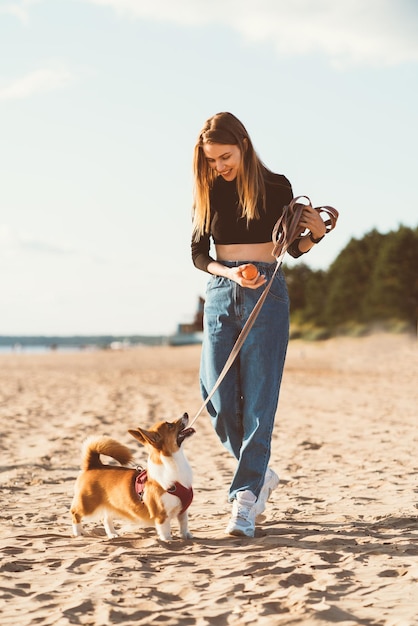 Foto mujer joven con perro en la playa.