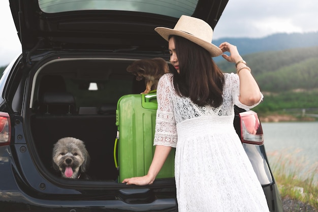 Foto mujer joven con perros de pie junto al coche estacionado
