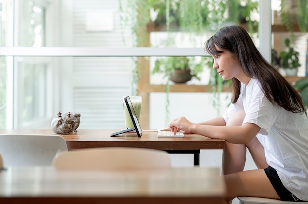 Mujer joven pertty usando la computadora mientras se queda en casa, trabaja desde el concepto de hogar.