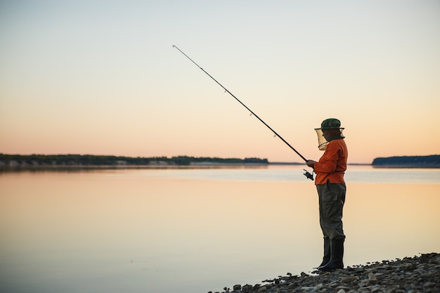 Mujer joven en la pesca con mosquitero con caña de pescar en la noche