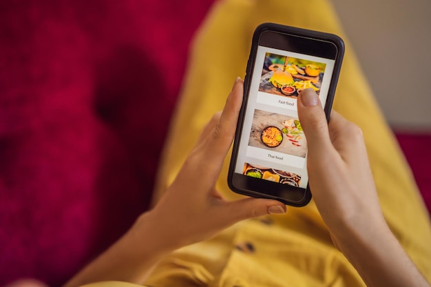 Una mujer joven pide comida para el almuerzo en línea usando un teléfono inteligente