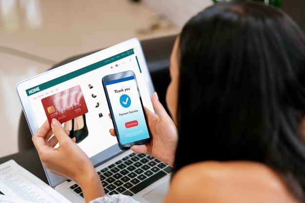 Mujer joven pide o compra un producto en Internet usando una computadora portátil y hace el pago de la transacción por teléfono inteligente Estilo de vida de compras en línea con tarjeta de crédito a través de la banca por Internet en la aplicación móvil Blithe.