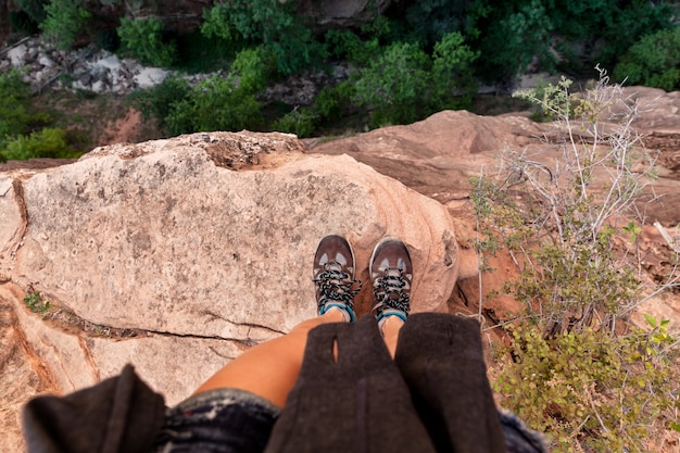 Mujer joven de pie al borde de una roca mirando hacia el cañón