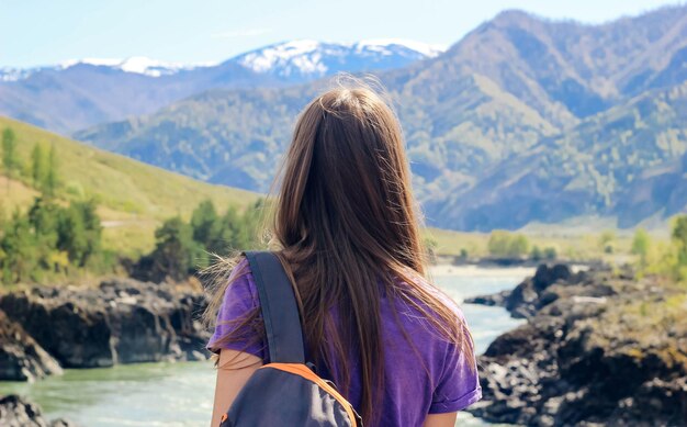 Mujer joven de pie hacia atrás y mirando el río en el paisaje montañoso Viajes de turismo concepto