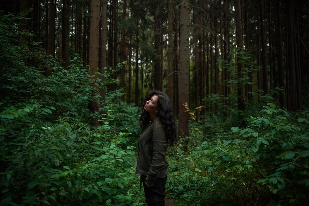Mujer joven de pie en el bosque