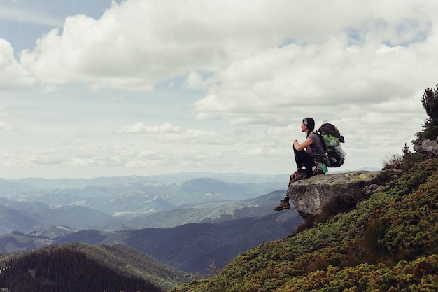 Mujer joven de pie en la cima del acantilado en las montañas de verano disfrutando de la vista de la naturaleza