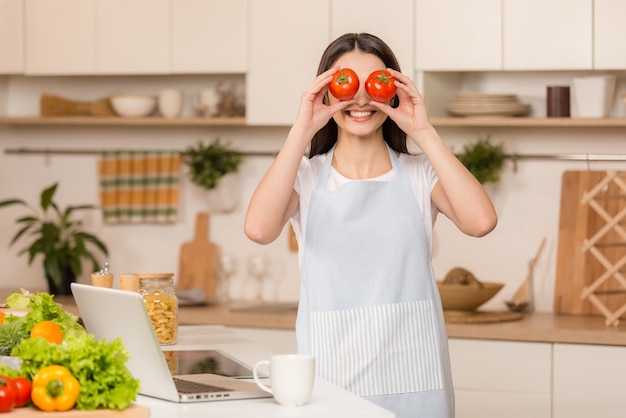 Mujer joven de pie en la cocina con portátil