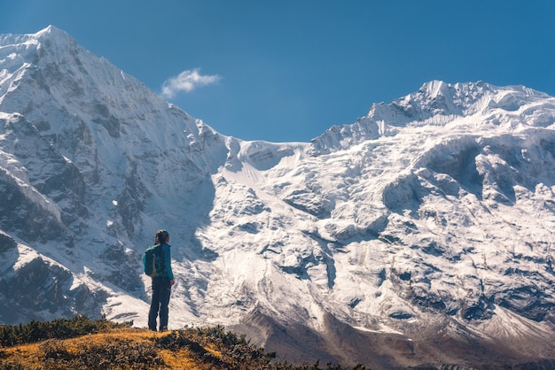 Mujer joven de pie en la colina y mirando increíbles montañas del Himalaya