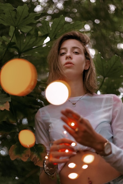 Foto mujer joven de pie contra un árbol iluminado