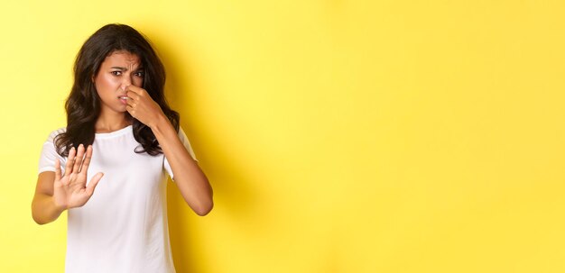 Mujer joven de pie contra un fondo amarillo