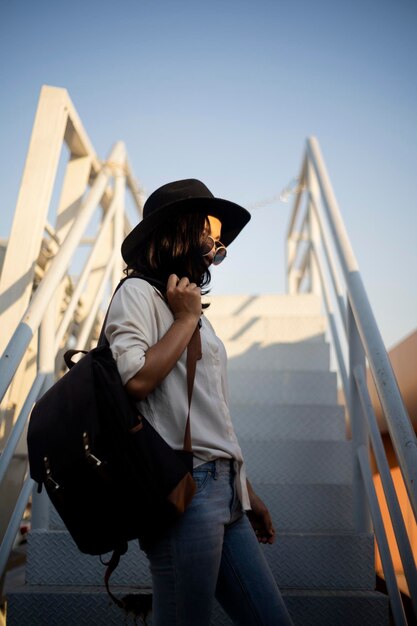 Foto mujer joven de pie por las escaleras contra el cielo