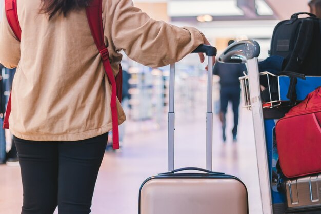 Mujer joven de pie y esperando después de registrarse con la maleta