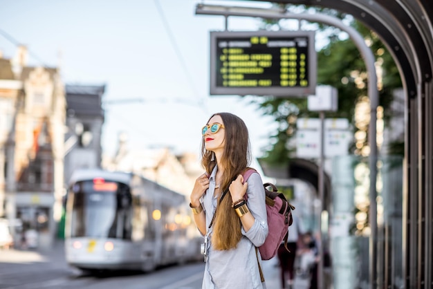 Mujer joven de pie en la estación de tranvía con horario en el casco antiguo de la ciudad de Gent en Bélgica