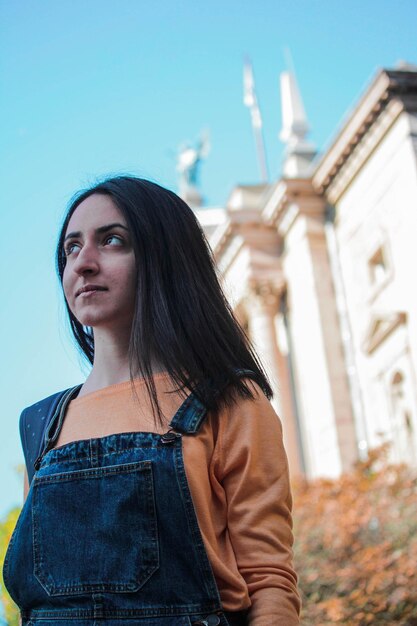 Foto mujer joven de pie fuera del edificio