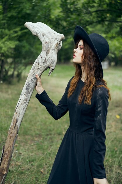 Foto mujer joven de pie junto al tronco del árbol