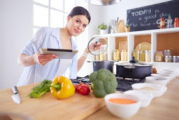 Mujer joven de pie junto a la estufa en la cocina