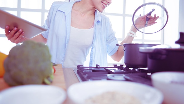 Mujer joven de pie junto a la estufa en la cocina