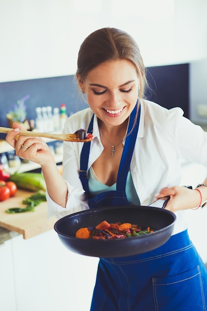 Mujer joven de pie junto a la estufa en la cocina