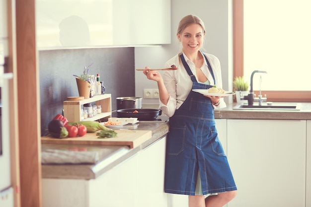 Mujer joven de pie junto a la estufa en la cocina
