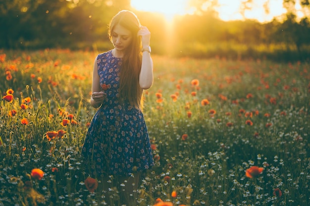 Mujer joven de pie en medio de las flores de amapola