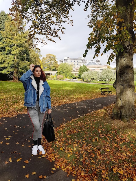 Foto mujer joven de pie en el parque durante el otoño