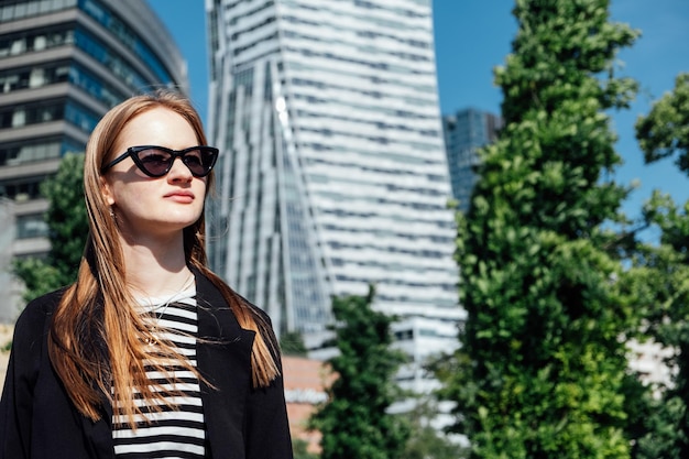 Mujer joven de pie sola mirando el moderno centro de la ciudad rascacielos calle vista de la ciudad