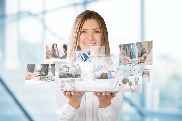 Mujer joven de pie y sonriendo con las caras de muchas personas diferentes volando desde su computadora de tableta.