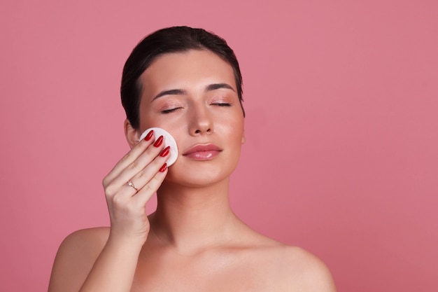 Mujer joven con piel limpia quita maquillaje con algodón