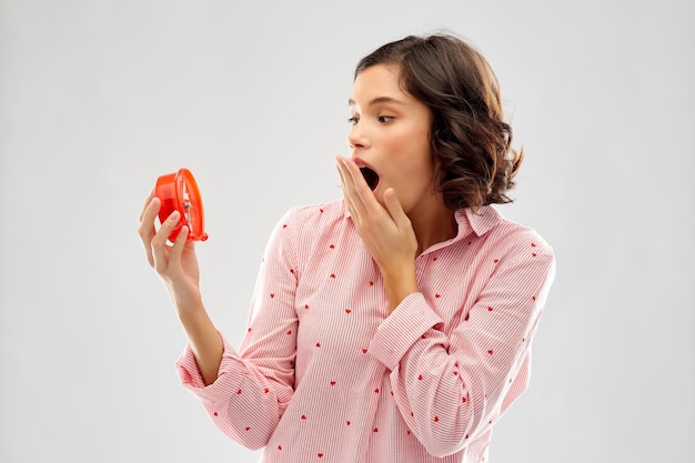 mujer joven con pijama con despertador