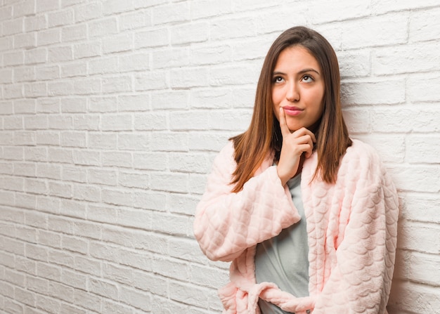 Mujer joven con pijama dudosa y confundida.