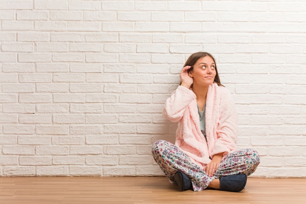 Mujer joven con pijama intenta escuchar un chisme