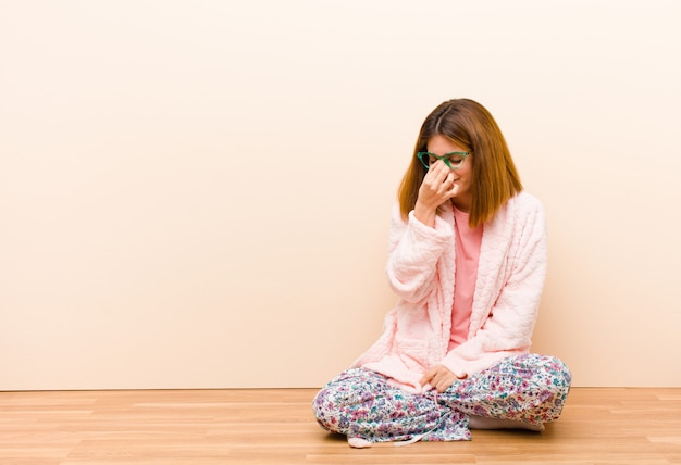 Foto mujer joven con pijama sentada en casa sintiéndose estresada, infeliz y frustrada, tocando la frente y sufriendo migraña de dolor de cabeza intenso