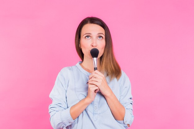 Mujer joven con un pincel de maquillaje