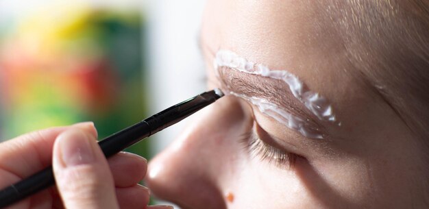 mujer joven pinta sus cejas con pintura cosmética