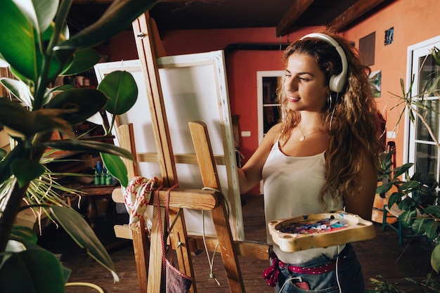 Foto mujer joven pintando en un caballete