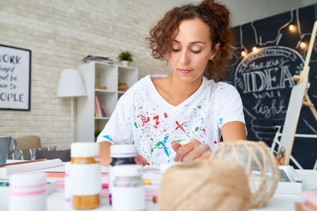 Mujer joven pintando cuadros en casa