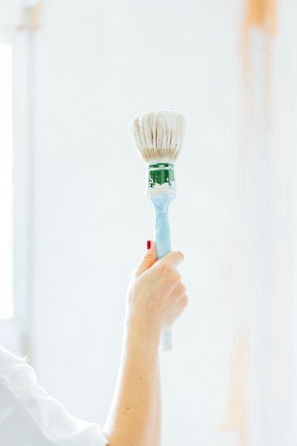 Mujer joven pintando las paredes de su casa.