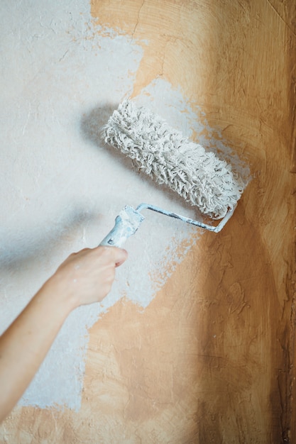 Mujer joven pintando las paredes de su casa.