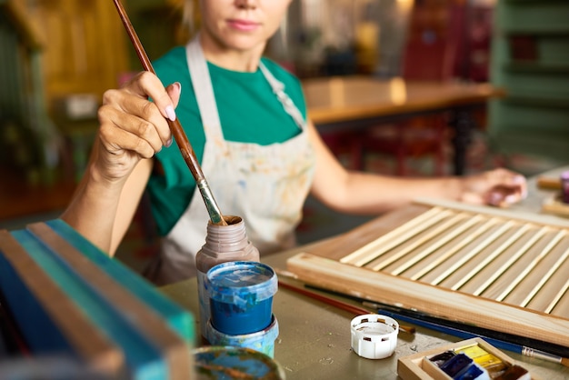 Mujer joven pintando proyecto de bricolaje en Art Studio