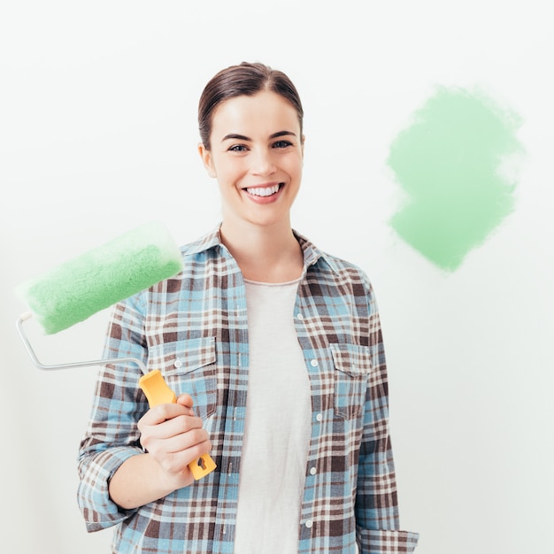 Foto mujer joven pintando su casa