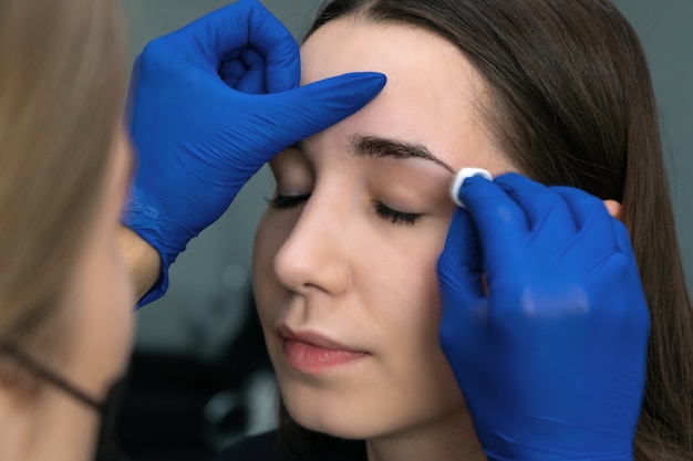 Mujer joven pinzas en las cejas en salón de belleza.