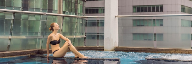 Mujer joven en la piscina entre los rascacielos y la gran ciudad relajarse en el descanso de la gran ciudad