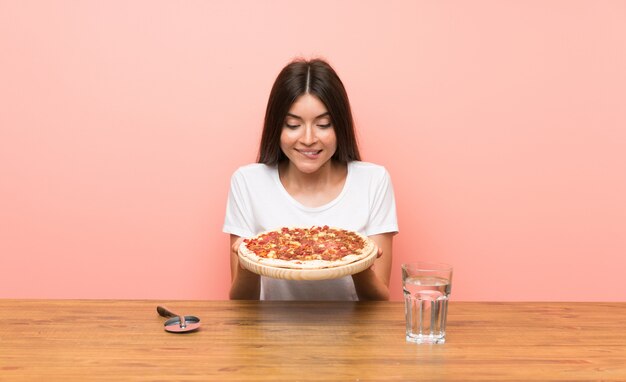 Mujer joven con una pizza en una mesa