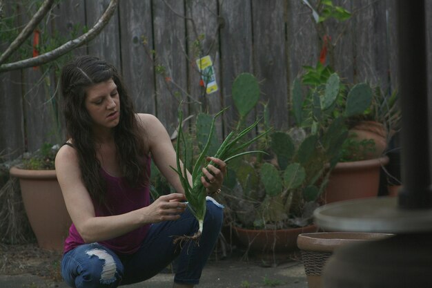 Mujer joven con una planta de aloe vera en el patio trasero