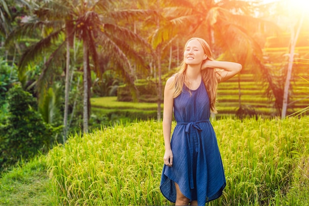 Mujer joven en la plantación de campo de arroz en cascada verde en la terraza de Tegalalang. Bali, Indonesia. con la luz del sol