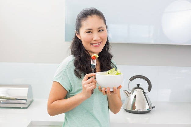 Mujer joven con un plato de ensalada en la cocina