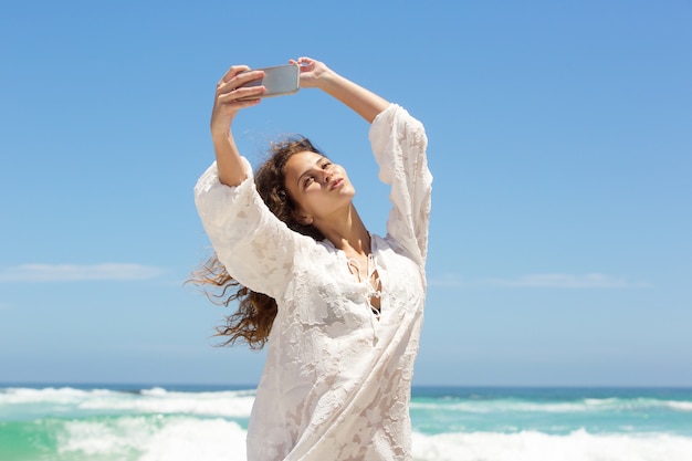 Mujer joven en la playa tomando selfie