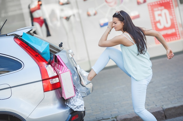 Mujer joven poniendo bolsas de compras en su coche