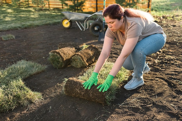 Mujer joven poniendo césped para el nuevo concepto de colocación de césped de césped de jardín